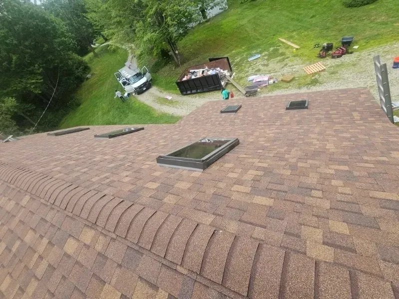 A roof with a skylight on it is being installed on a house.