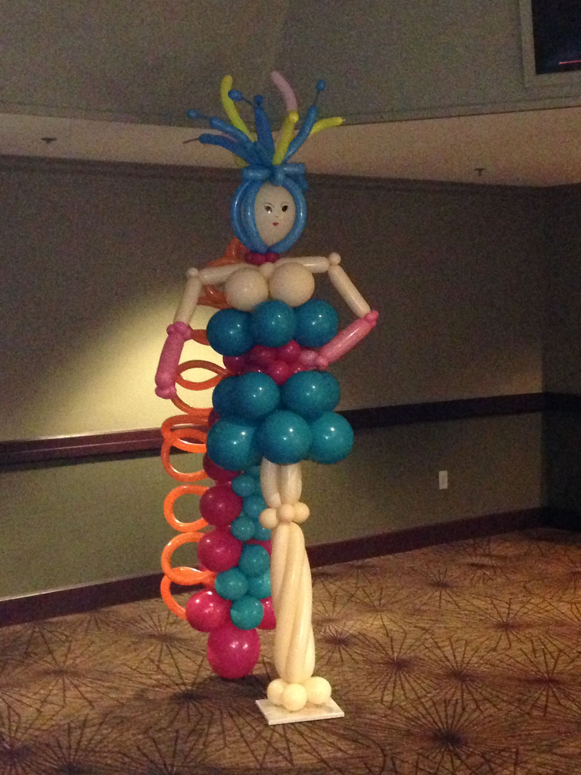 A woman made out of balloons is standing in a room