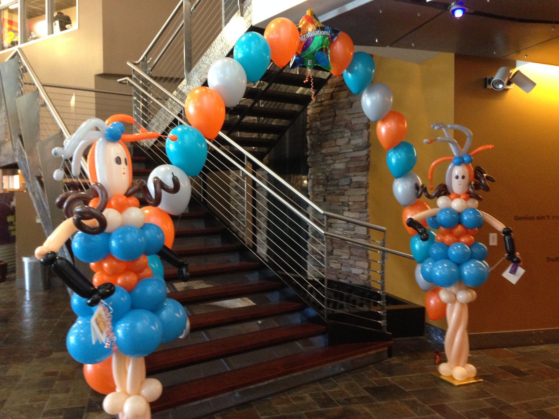 Two balloon figures are standing in front of a staircase