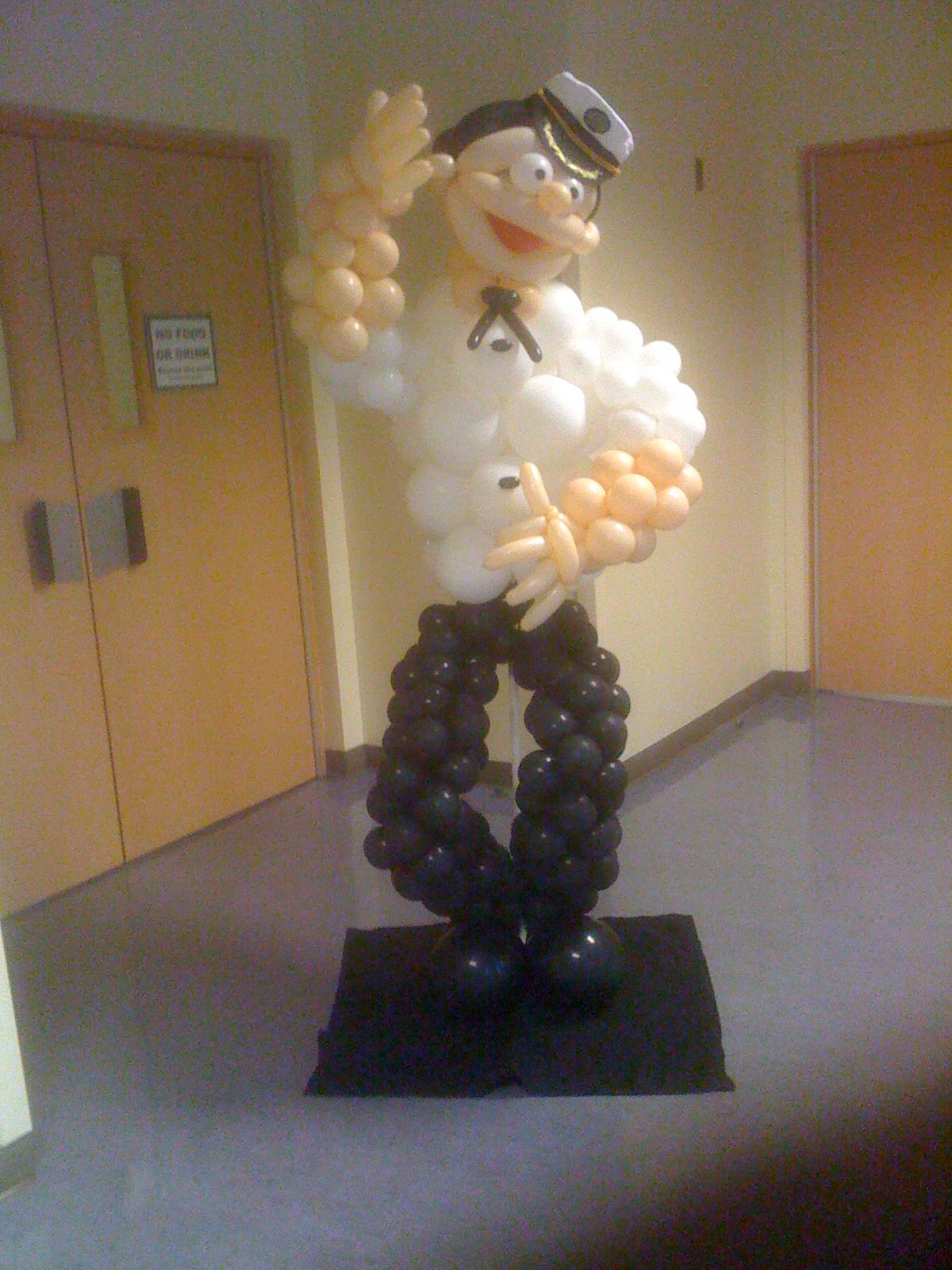 A man made out of balloons is standing in a hallway.