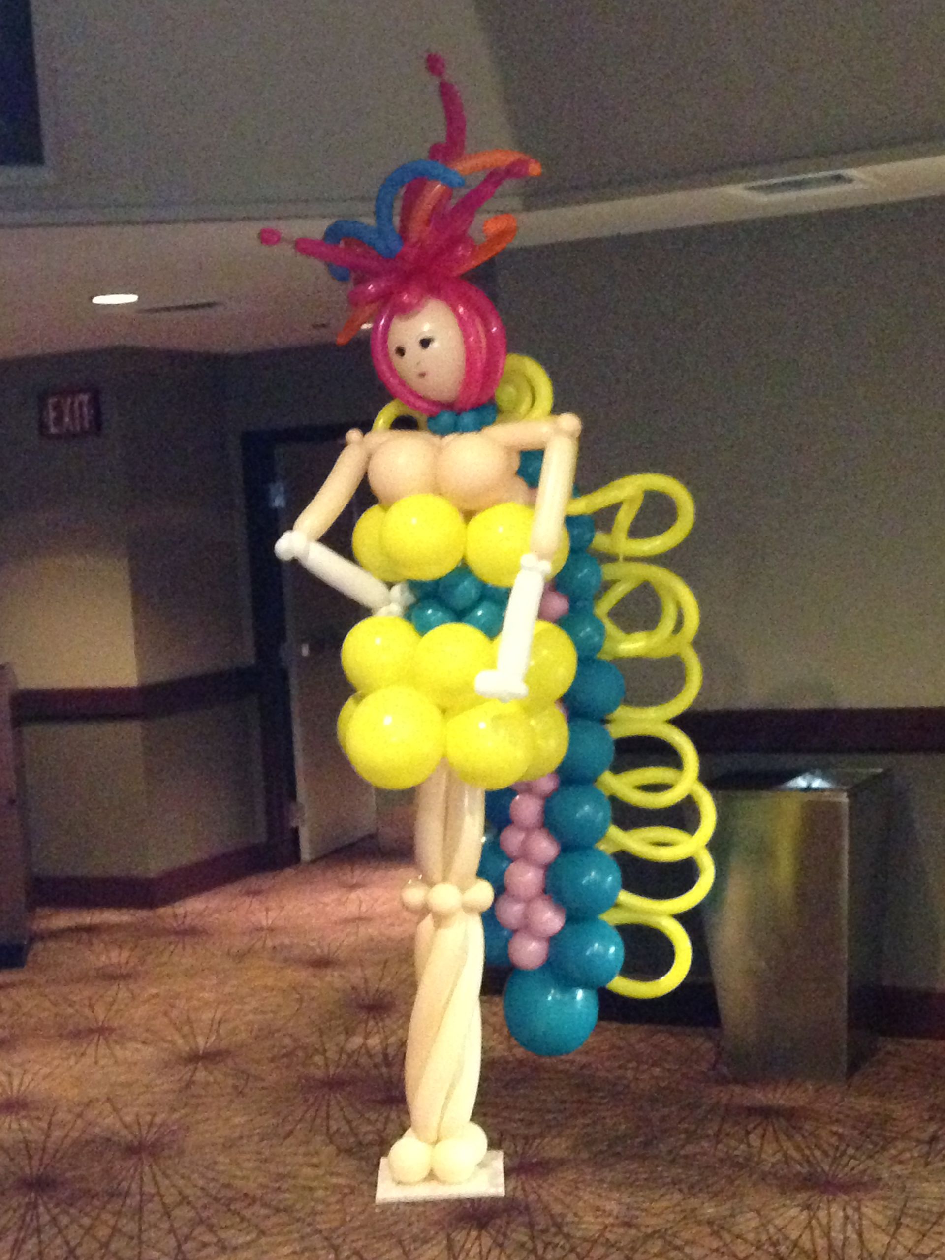 A woman made out of balloons is standing in front of an exit sign