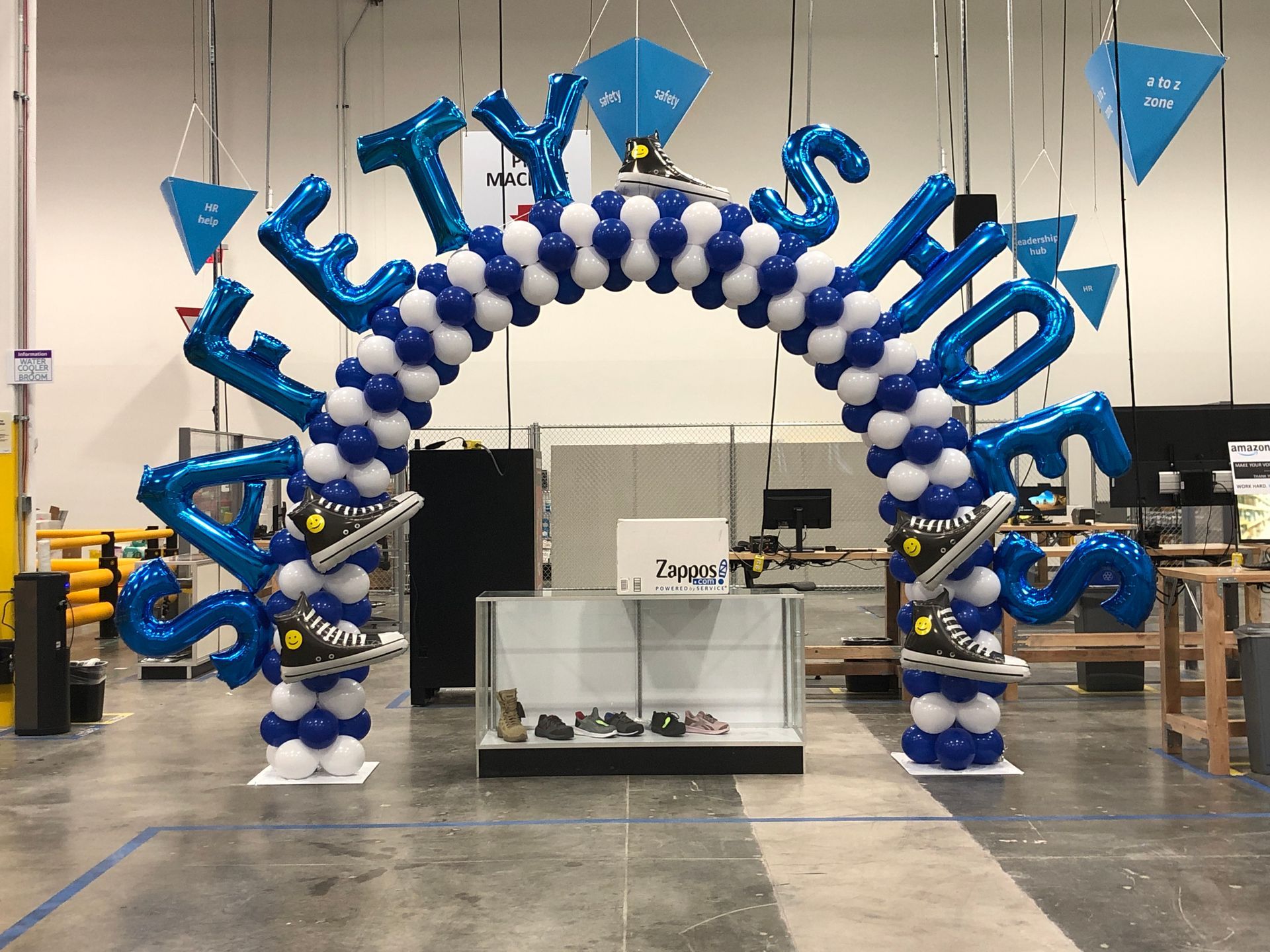 A blue and white balloon arch with the word shoes on it