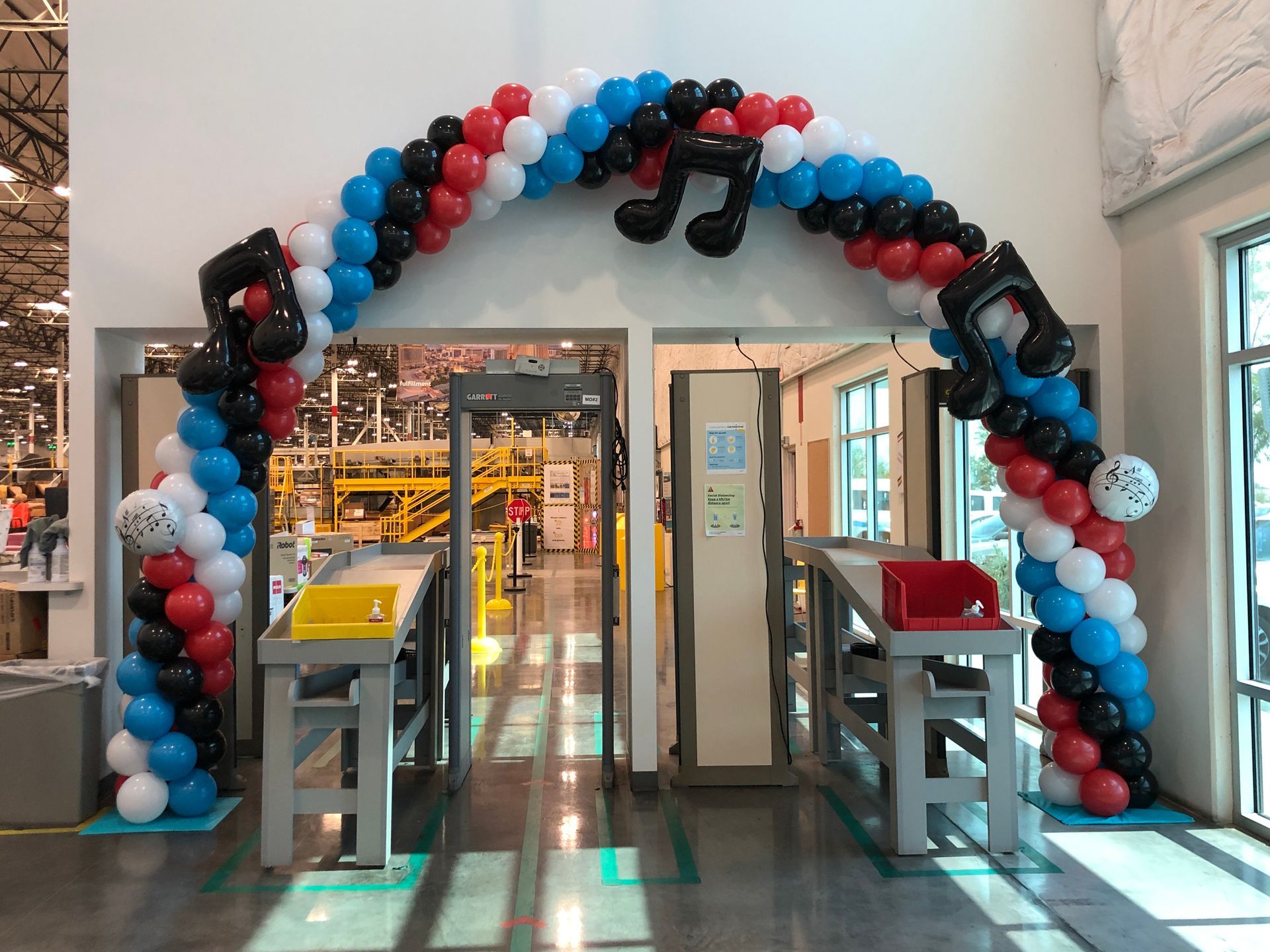 A large arch made of red , white , and blue balloons in a room.