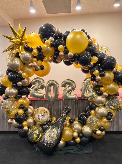 A wreath of balloons with a bottle of champagne in the middle.
