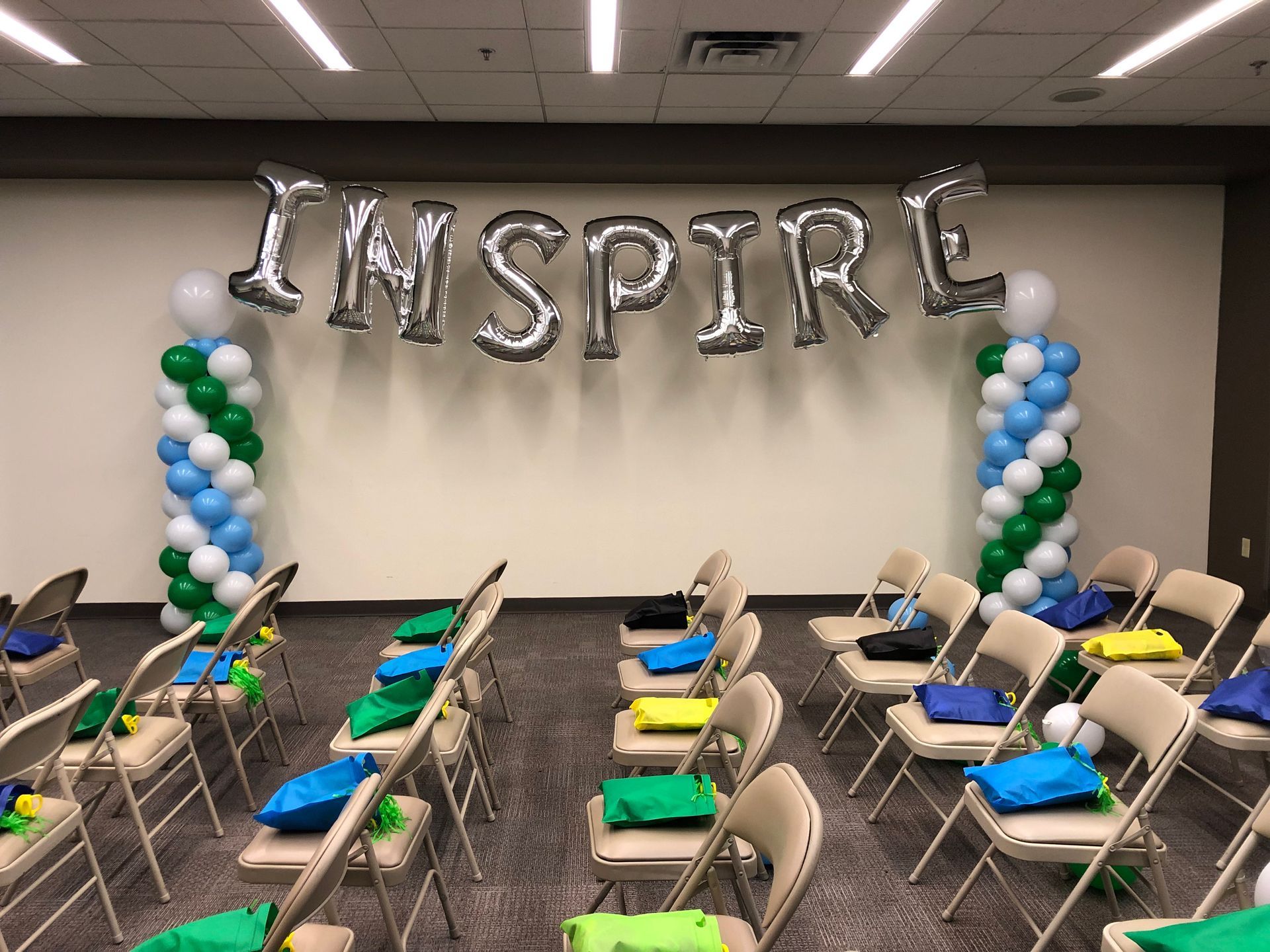 A room with chairs and balloons that say inspire