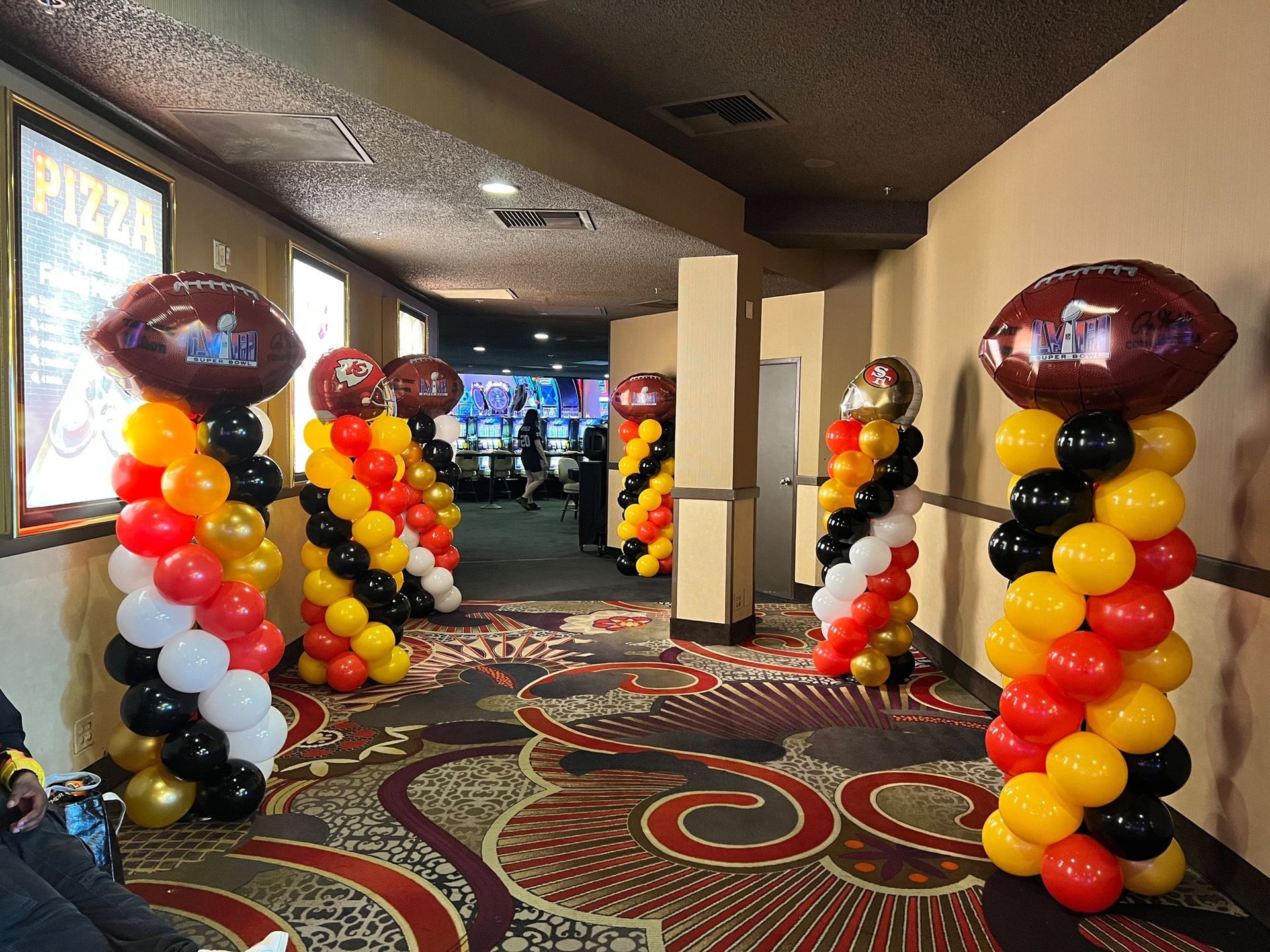 A hallway filled with balloons and a sign that says pizza