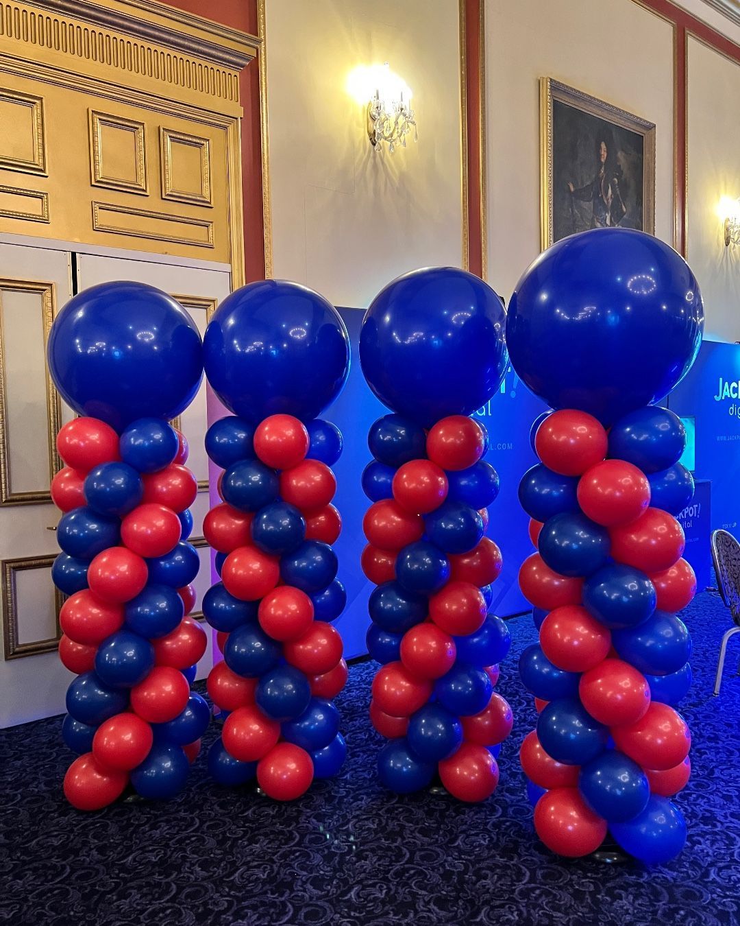 Four columns of red and blue balloons in a room