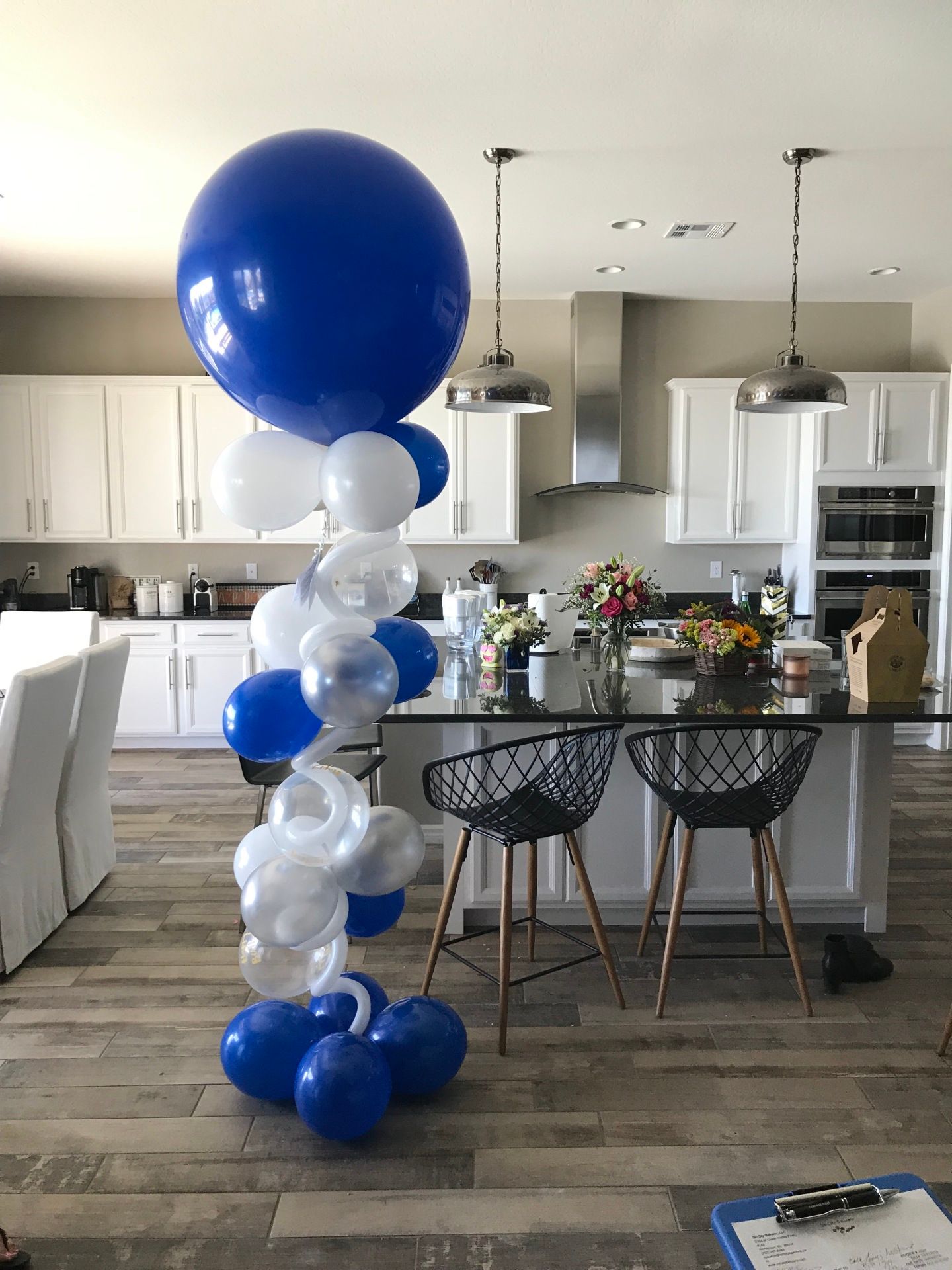 A bunch of blue and white balloons are sitting in a kitchen.