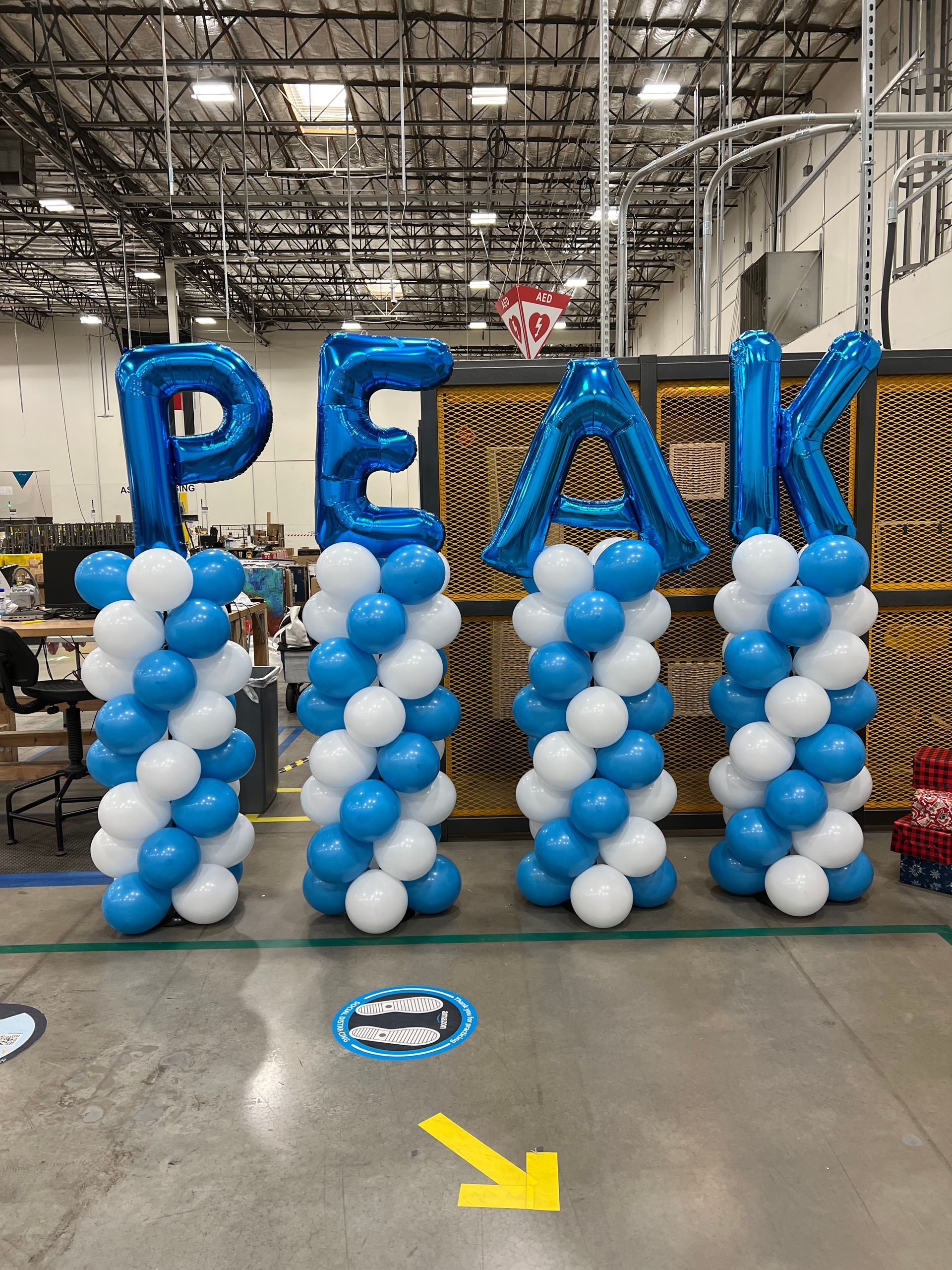Blue and white balloons are arranged in the shape of the word peak