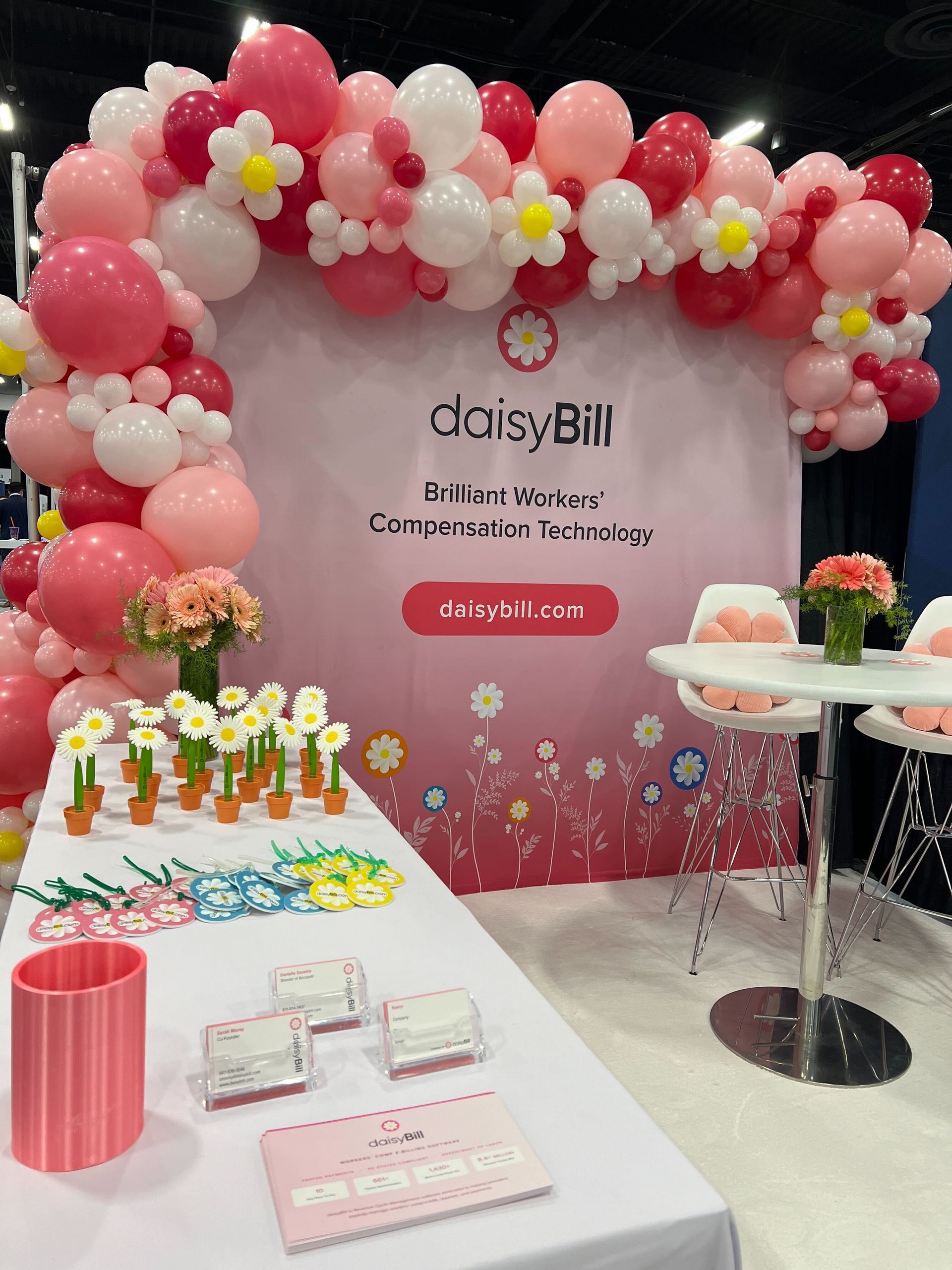 A table with balloons and flowers on it in front of a pink wall.