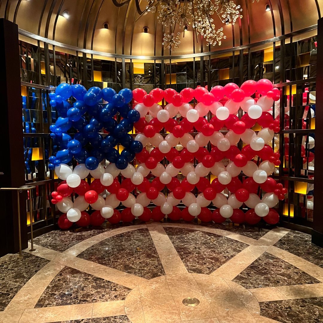 A wall of red white and blue balloons in the shape of an american flag