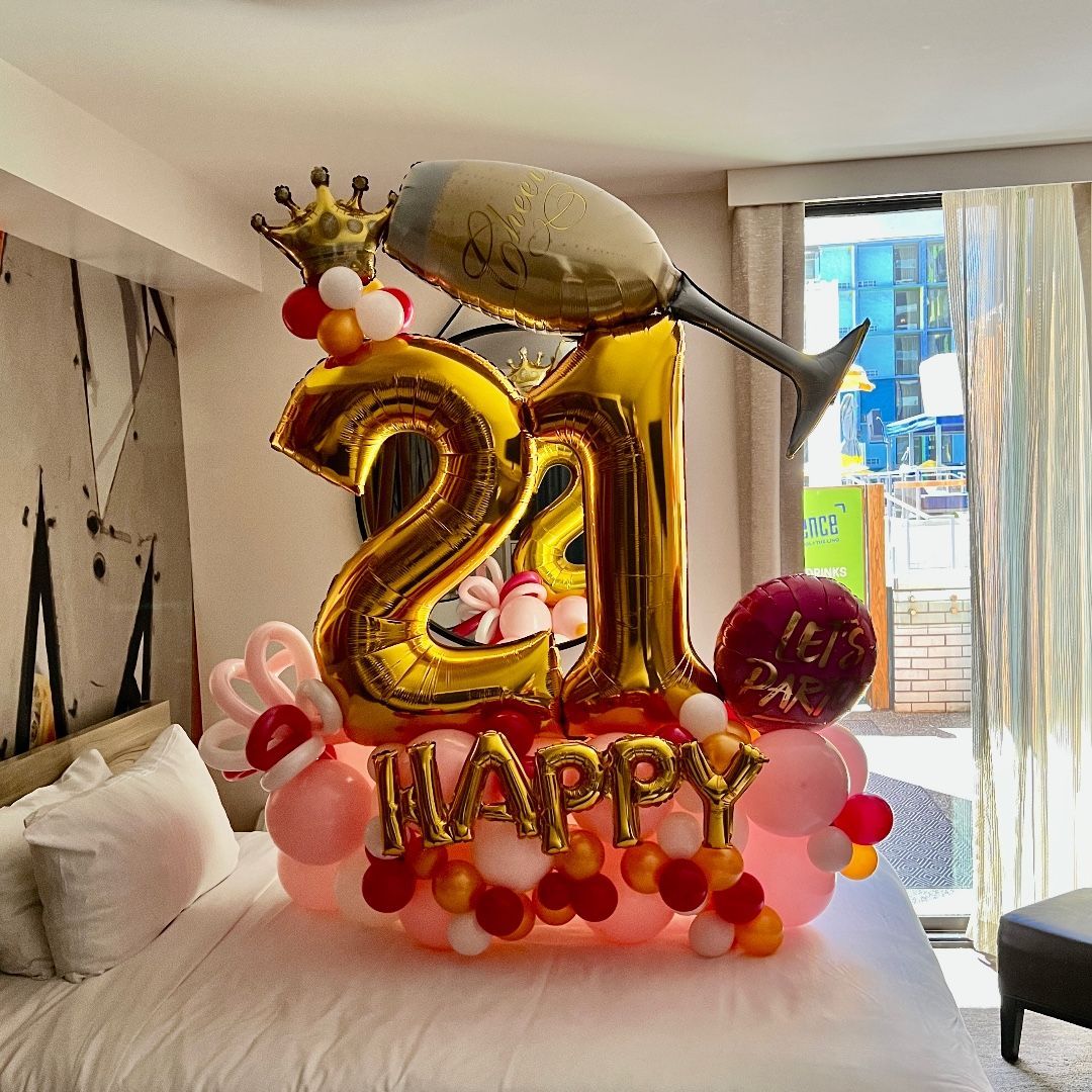 A bedroom with a bed , balloons , and a champagne glass.