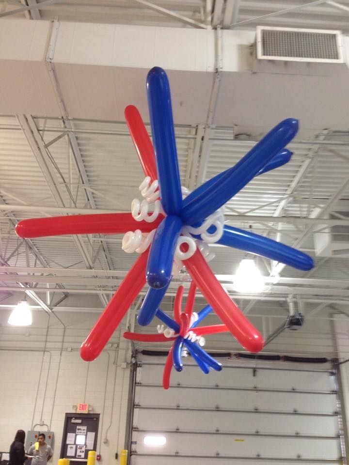 A bunch of red white and blue balloons hanging from the ceiling