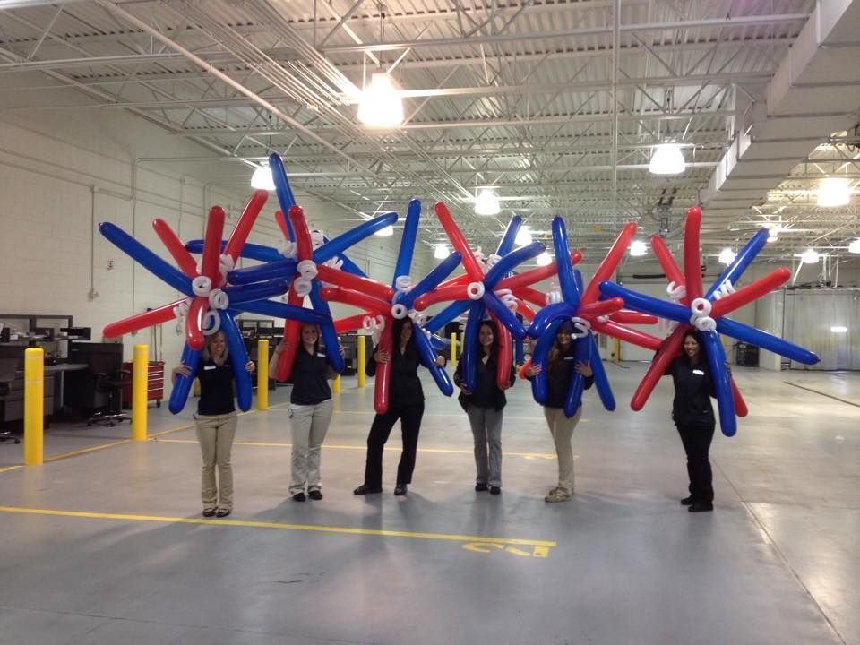 A group of people holding red white and blue balloons