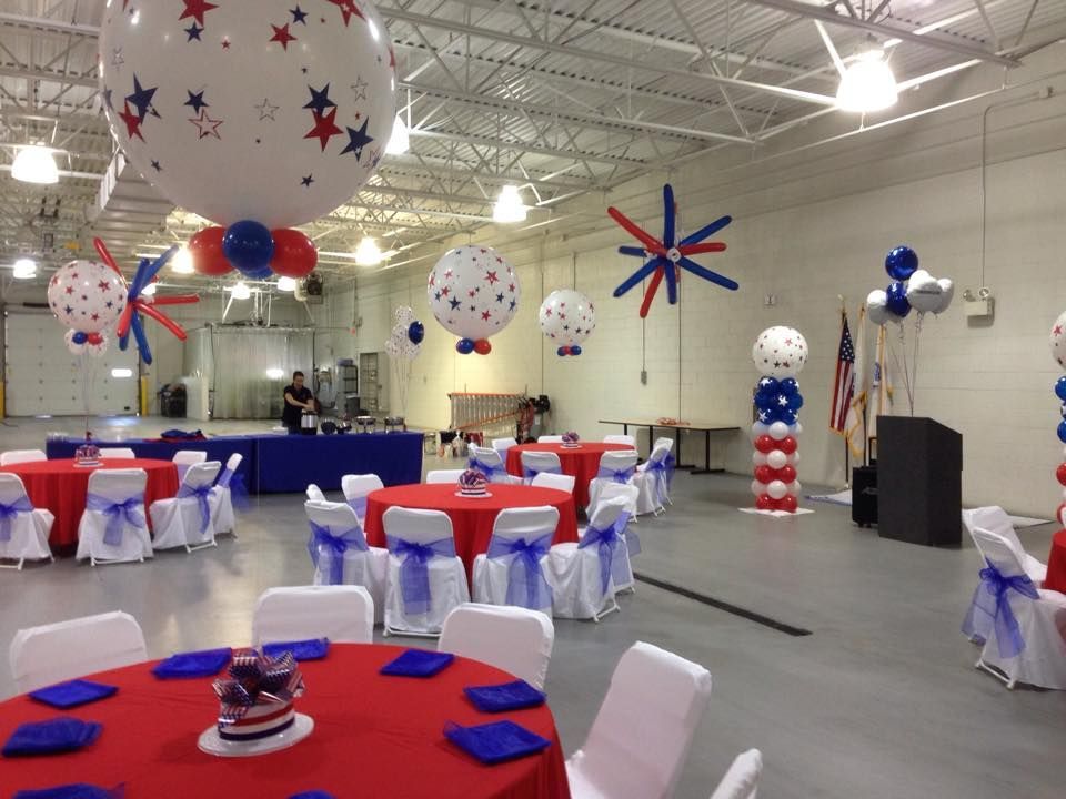 A large room with tables and chairs decorated with red white and blue balloons