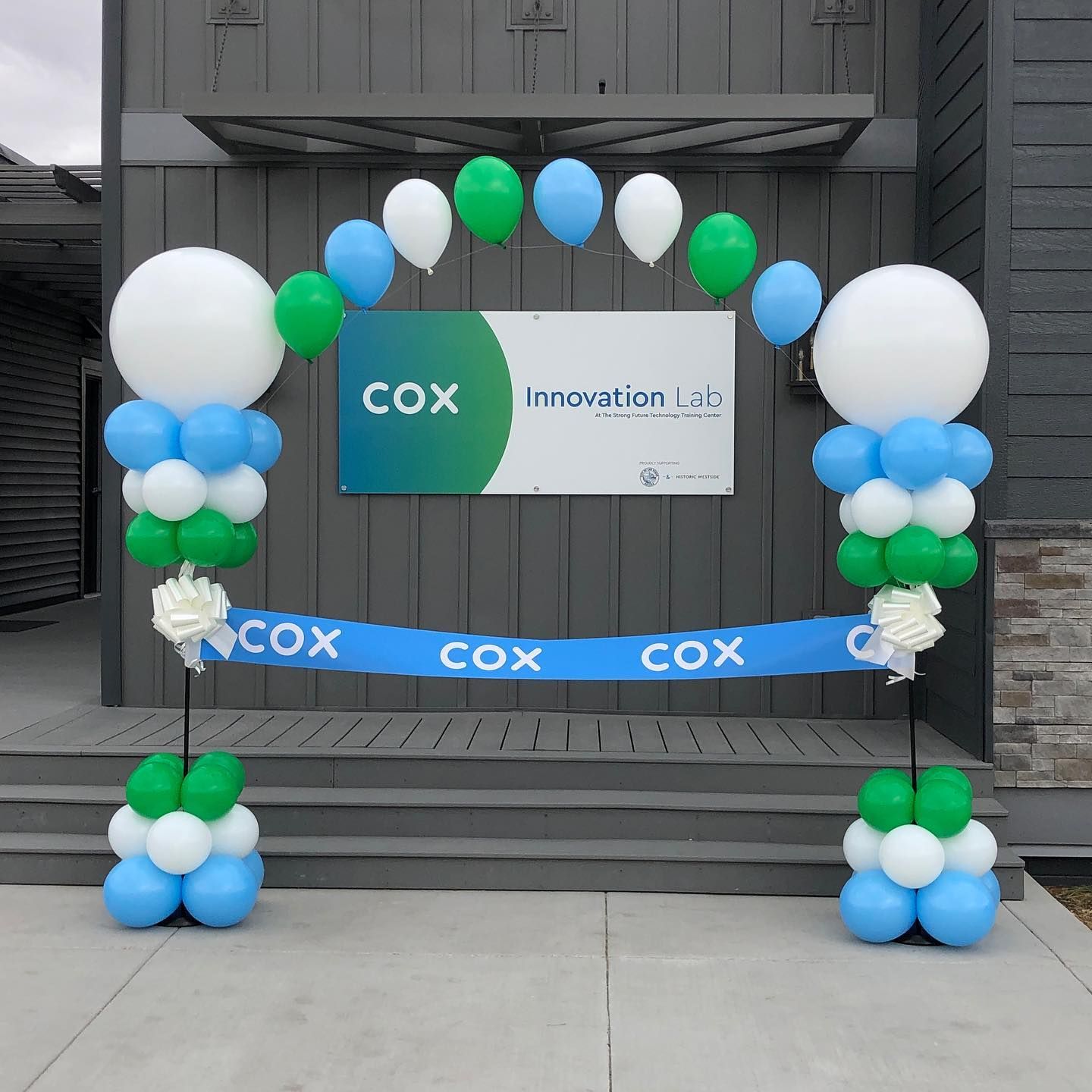 A sign that says cox innovation is surrounded by balloons