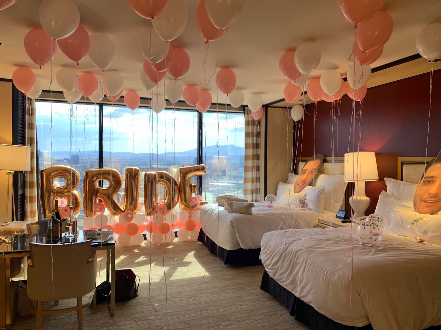A hotel room decorated for a bachelorette party with balloons hanging from the ceiling.