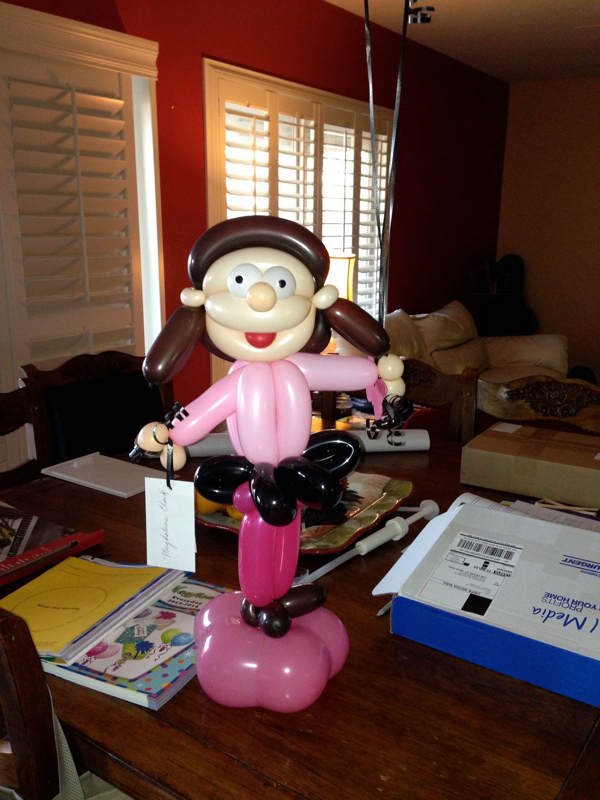An orange and blue balloon arch in a gym with the word orma on the floor