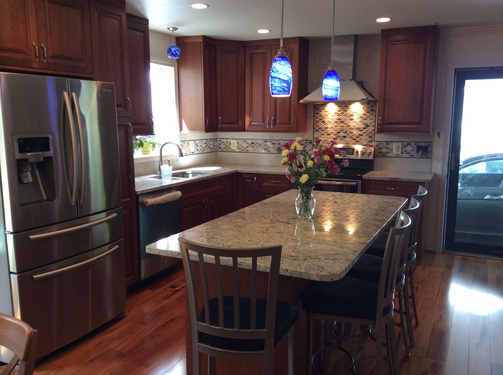 Modern kitchen with cherry cabinets, granite countertops, stainless steel appliances, and island with seating.