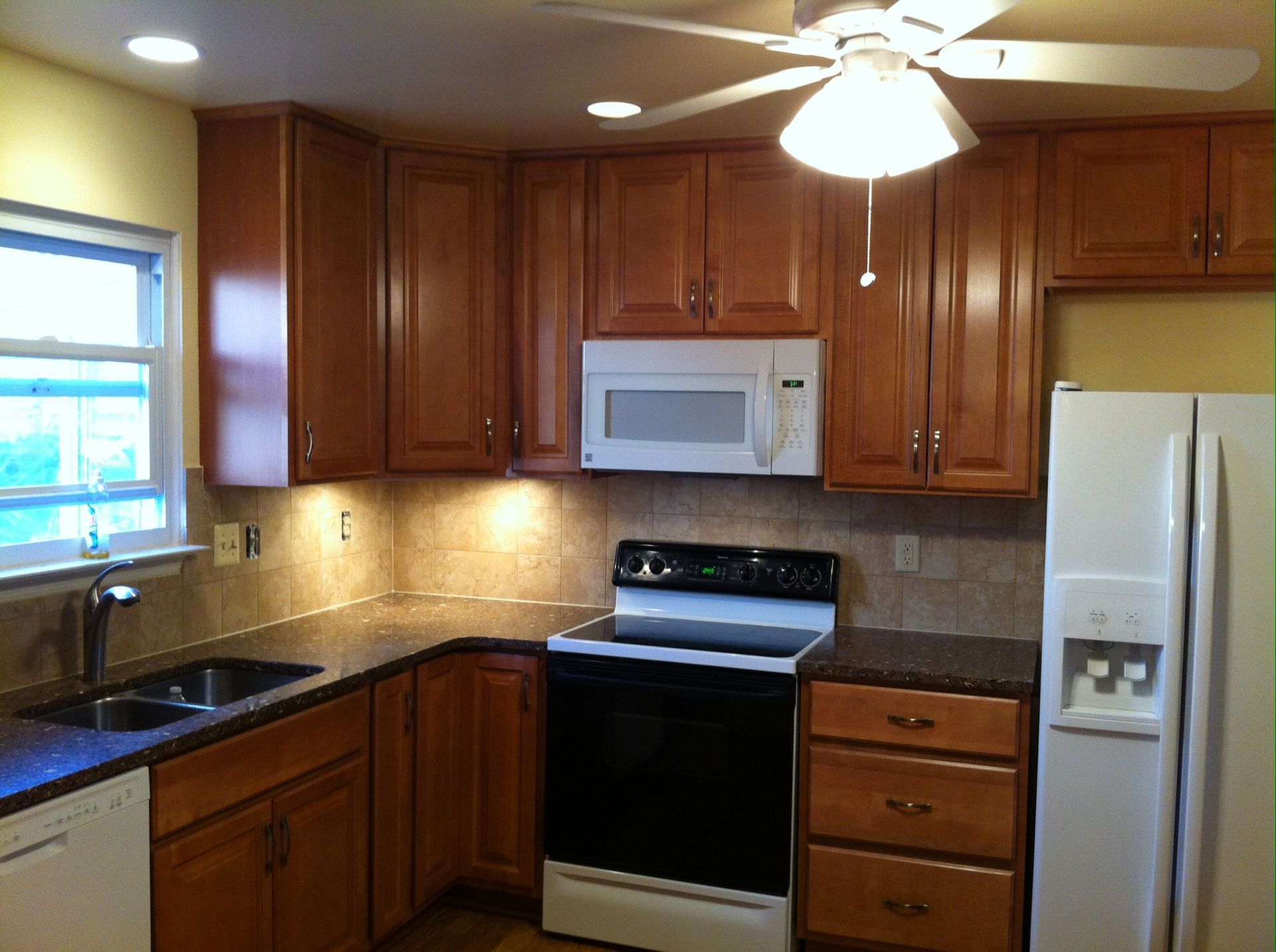Kitchen with brown cabinets, white appliances, and a microwave above the stove.