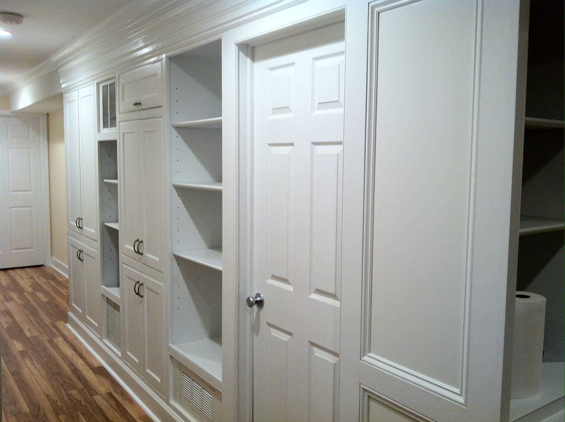 A hallway with lots of white cabinets and shelves