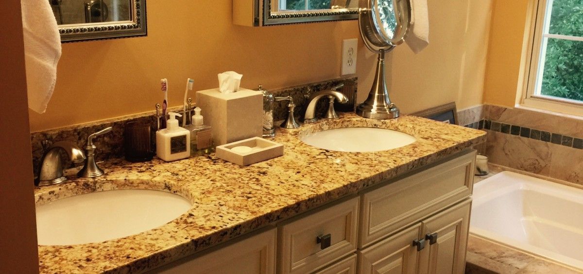 Bathroom vanity with two sinks, granite countertop, and a bathtub.