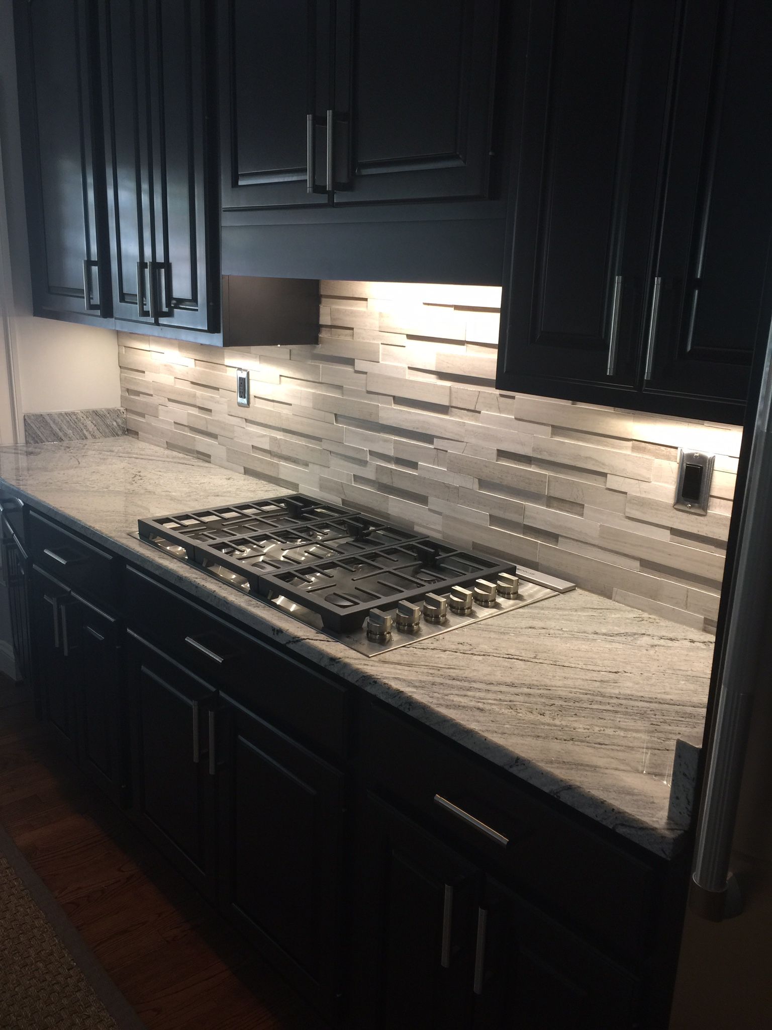 A kitchen with black cabinets and a stove top oven.