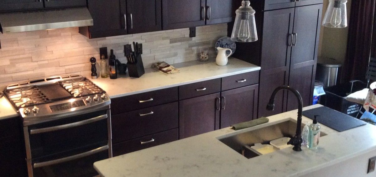 Kitchen with dark cabinets, white countertops, and stainless steel appliances.