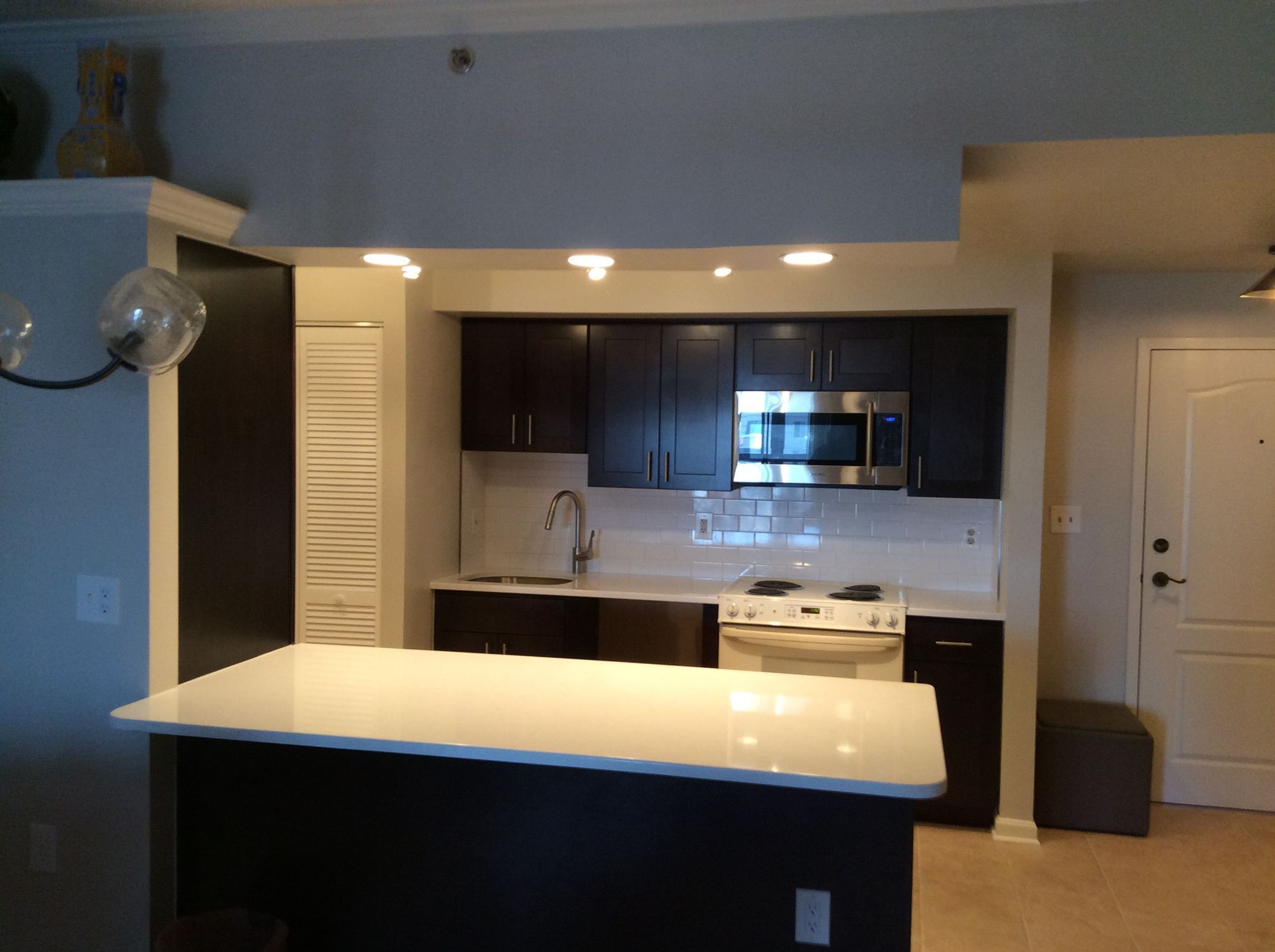 Modern kitchen with dark brown cabinets, white countertops, and a white tile backsplash.