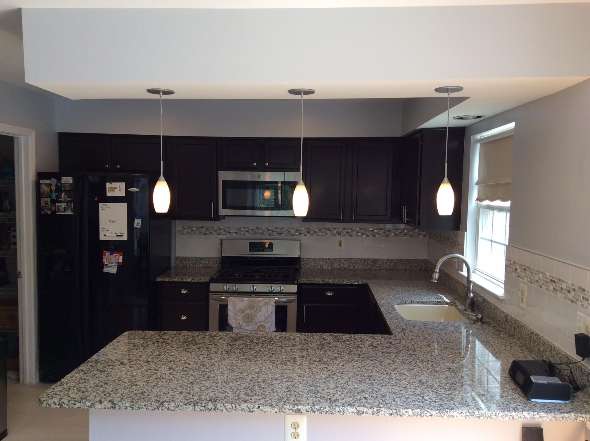 Kitchen with dark cabinets, granite countertops, and three pendant lights.