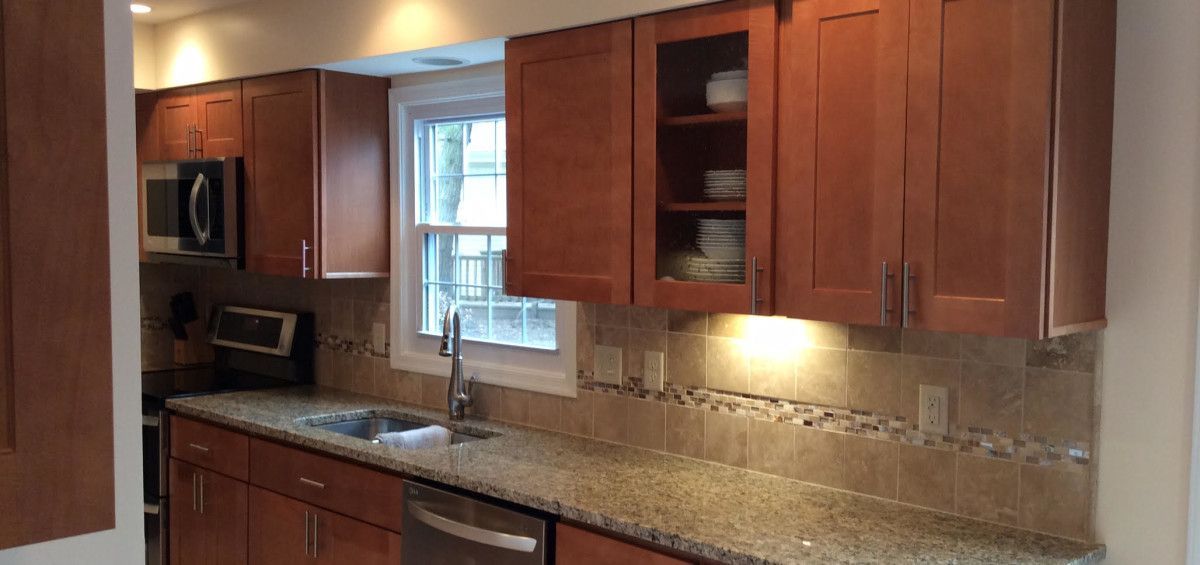 Kitchen with brown cabinets, granite countertops, and a window.