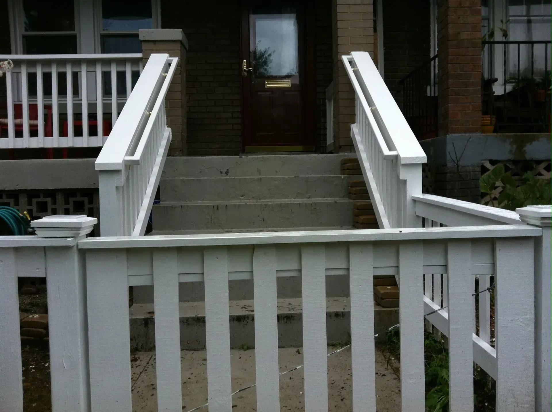 White picket fence and stairs leading to a front door with white railings on either side.
