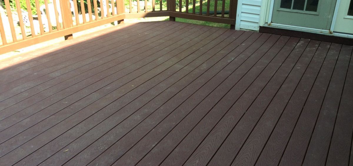Wooden deck with brown planks and railing.