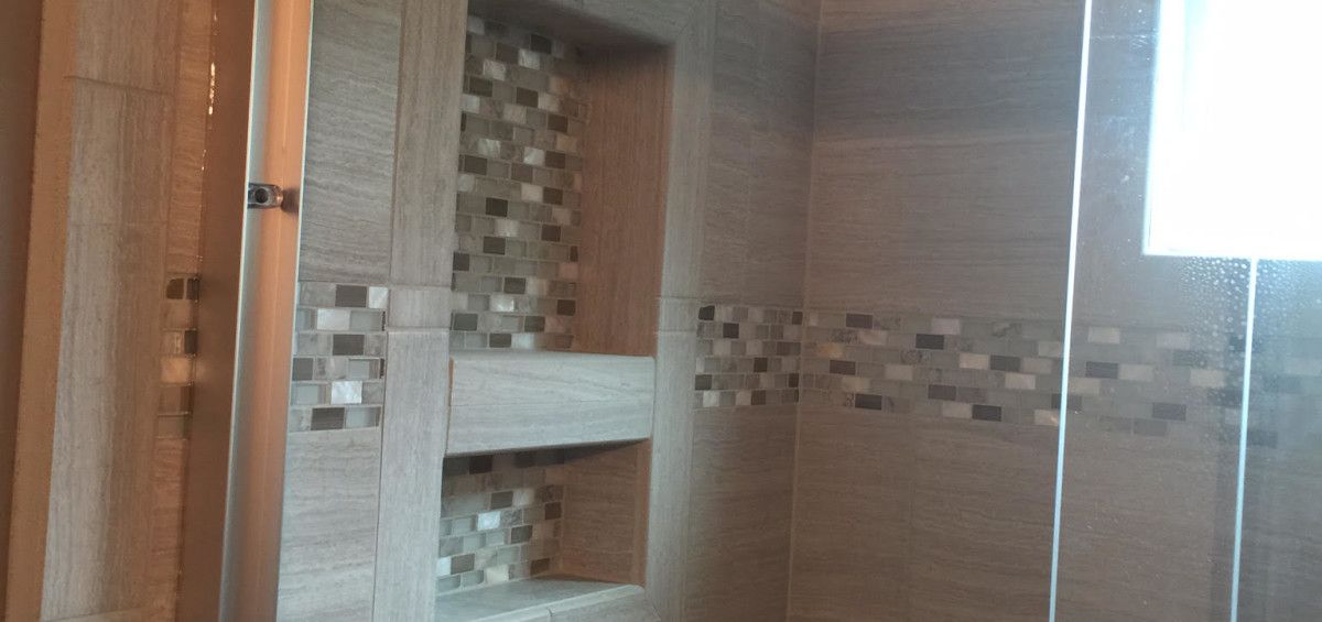 Shower interior with tile walls, a built-in niche, and glass door.