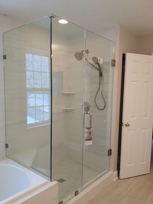 Glass shower enclosure with white tile and fixtures, beside a closed white door.