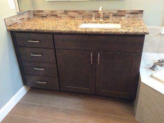Dark brown bathroom vanity with granite countertop, sink, and drawers.