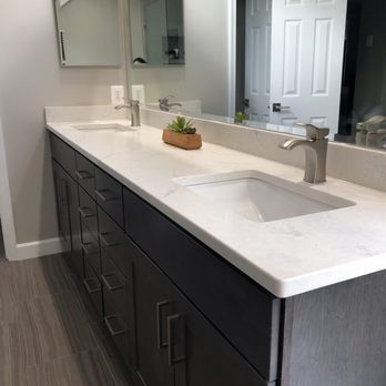 Bathroom with double sinks, gray countertop, dark wood cabinets, and large mirror.