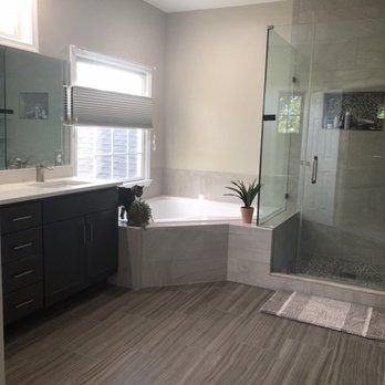 Modern bathroom with dark cabinets, a corner tub, and a glass shower.