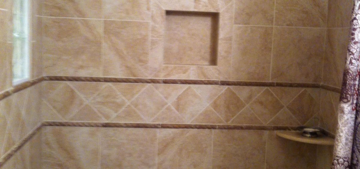 Bathroom interior with tan tiles, diamond pattern, and a built-in shelf.