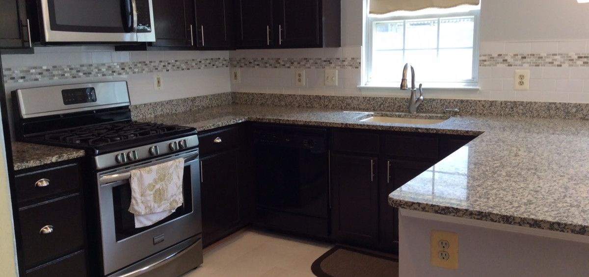 Kitchen with dark cabinets, granite countertops, and stainless steel appliances.