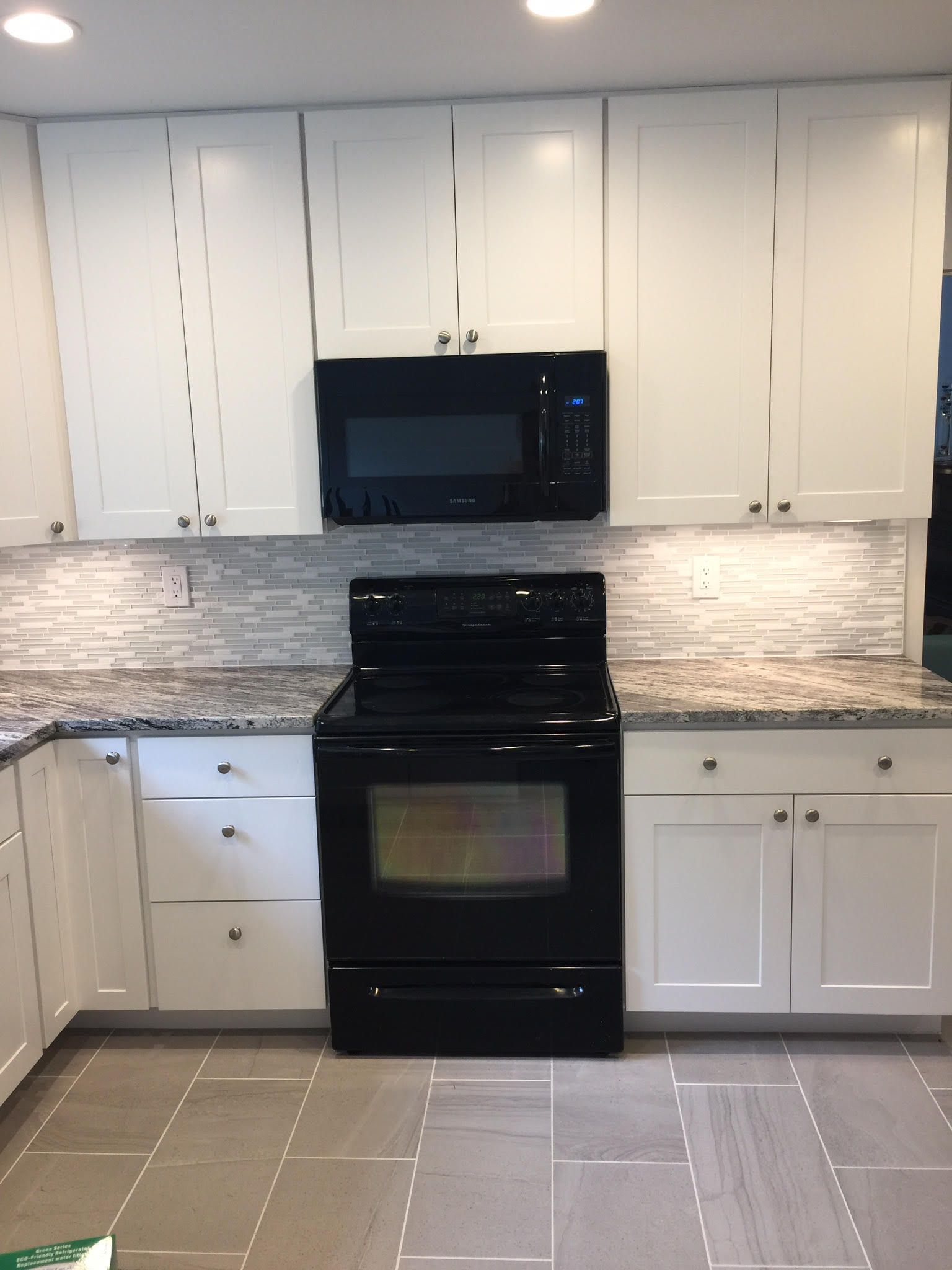 White kitchen cabinets with a black microwave and oven.