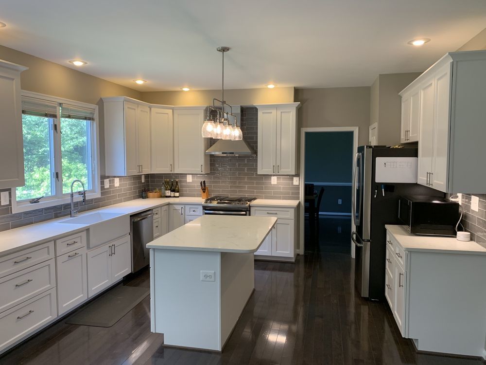 A kitchen with white cabinets , stainless steel appliances , and a large island.