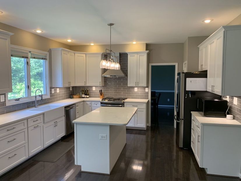 A kitchen with white cabinets , stainless steel appliances , and a large island.