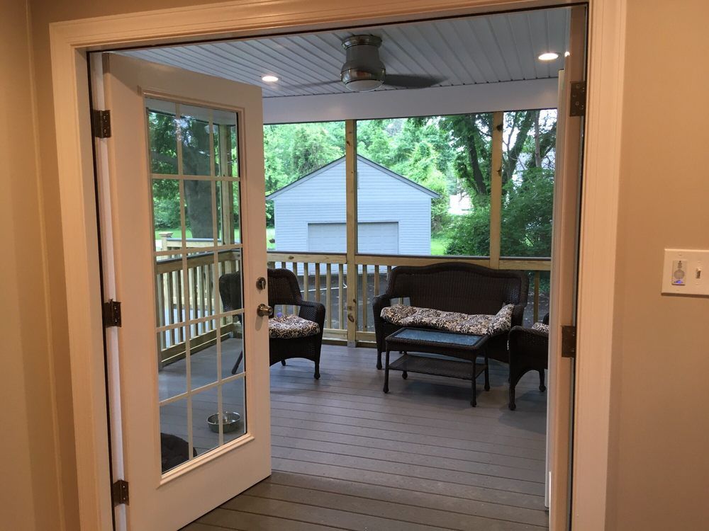 Open French doors to a screened porch with outdoor furniture, and a shed in the background.