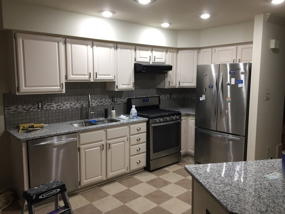 Kitchen with off-white cabinets, stainless steel appliances, gray countertops, and checkered floor.