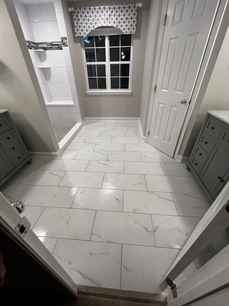 Bathroom with white tiled floor, shower, window, and two grey vanities.