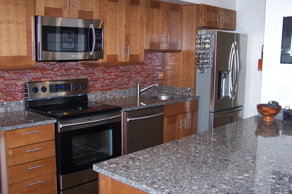 Modern kitchen with stainless steel appliances, granite countertops, and wooden cabinets.