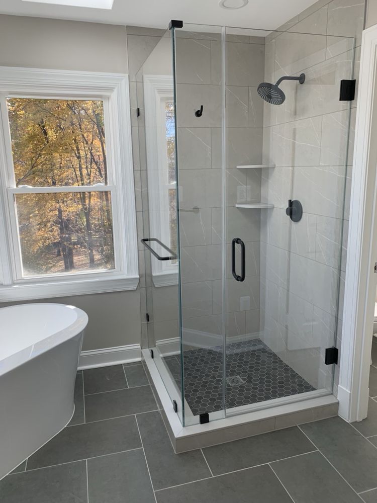 Modern bathroom with a glass shower, gray tiles, and a freestanding tub.