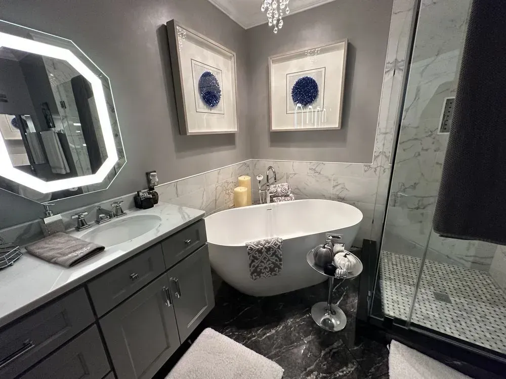 Elegant gray and white bathroom with a soaking tub and marble accents.