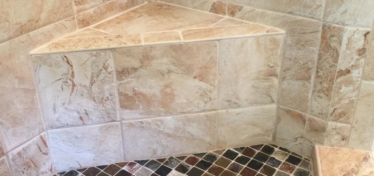 Corner shower with tile walls and a mosaic tile floor.